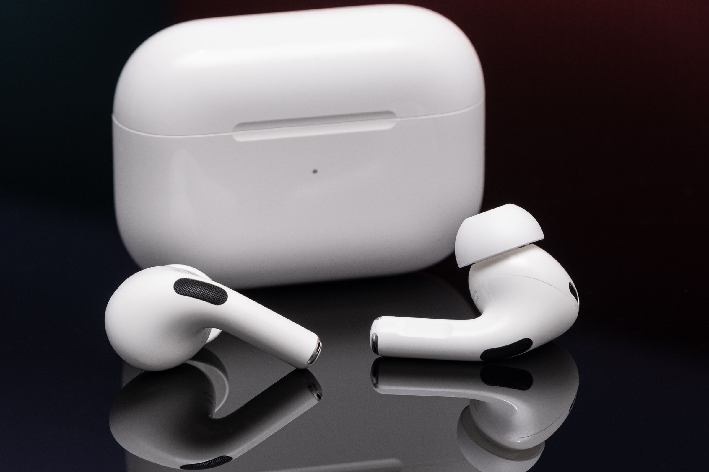 Τα AirPods Pro δεύτερης γενιάς της Apple φωτογραφήθηκαν σε μια ανακλαστική μαύρη επιφάνεια.