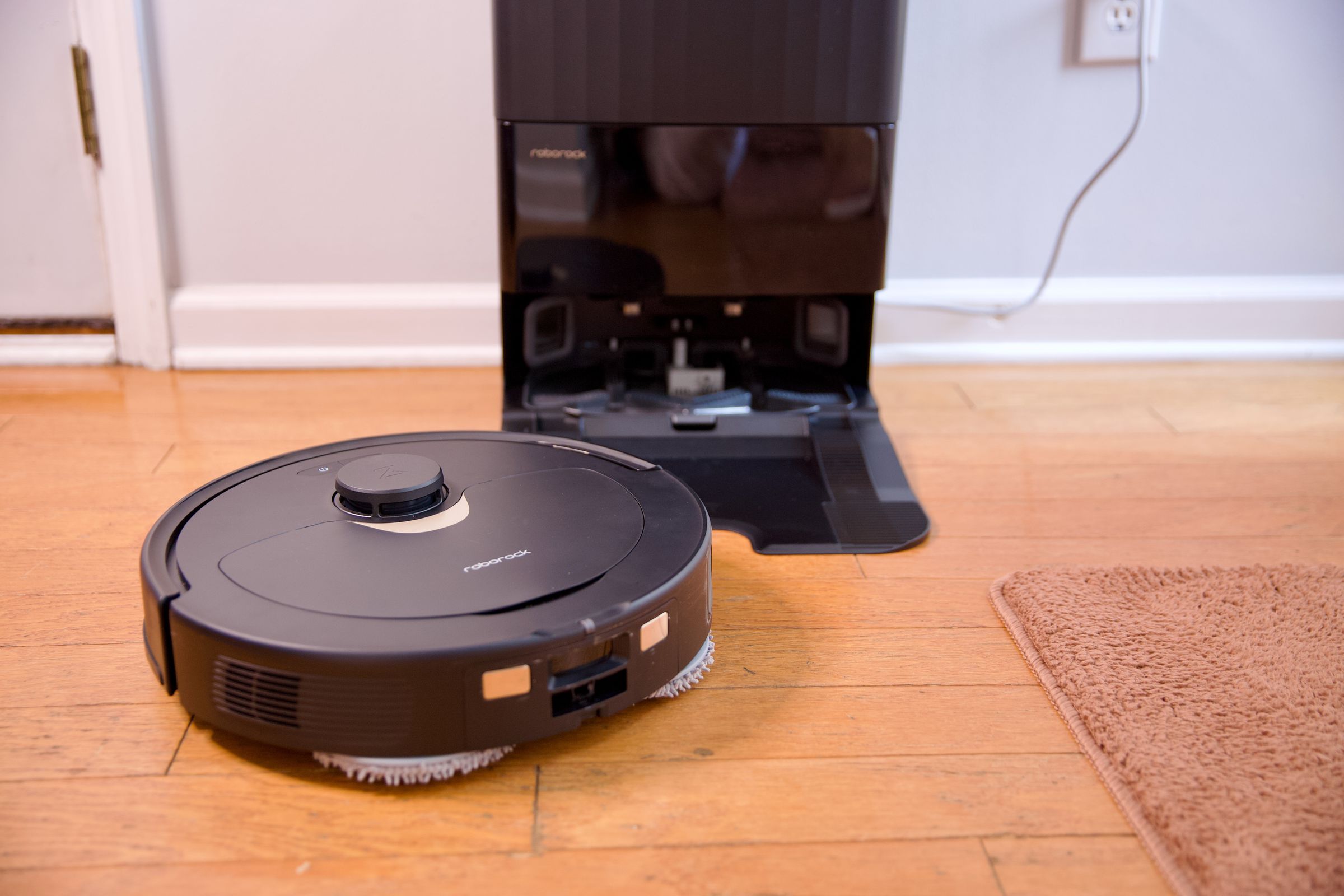 Roborock's Q Revo robot vacuum sitting on a hardwood floor with its charging dock.