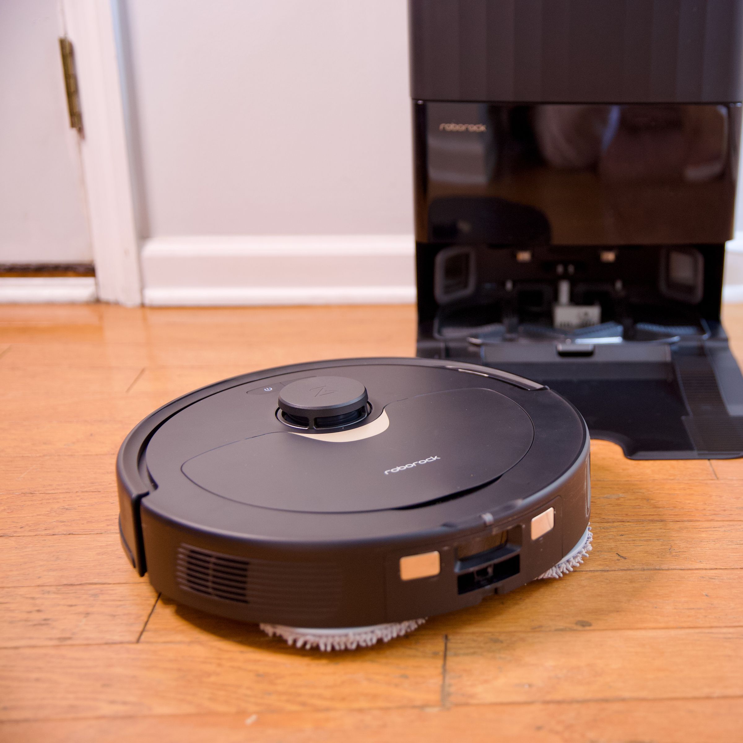 Roborock's Q Revo robot vacuum sitting on a hardwood floor with its charging dock.