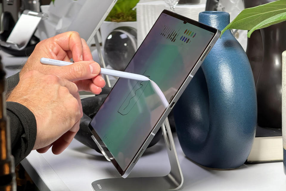 Πλάγια όψη ενός Galaxy Tab S10 Ultra σε βάση με ένα χέρι που κρατά ένα στυλό S και σχεδιάζει πάνω του.