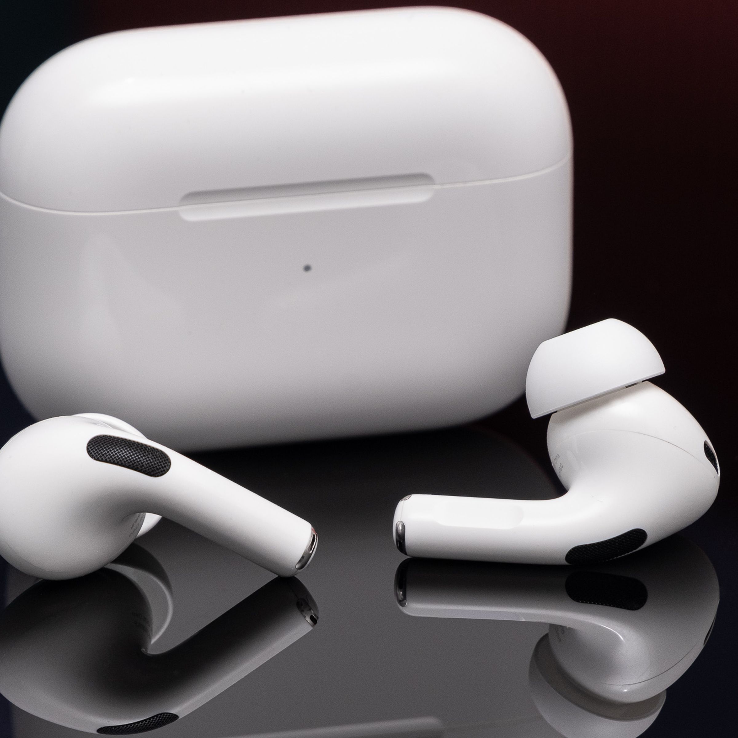 Τα AirPods Pro δεύτερης γενιάς της Apple φωτογραφήθηκαν σε μια ανακλαστική μαύρη επιφάνεια.