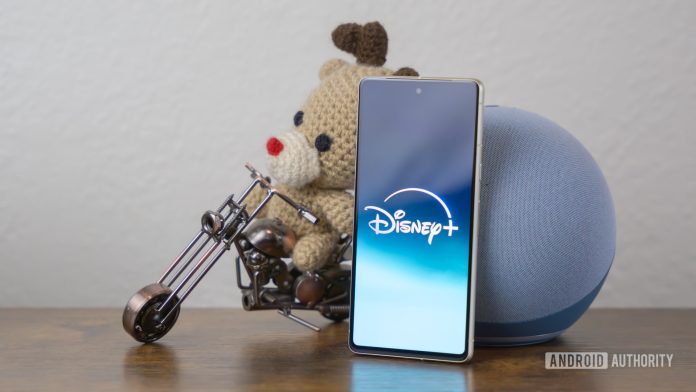 Disney Plus logo on smartphone laying on side table stock photo (2)