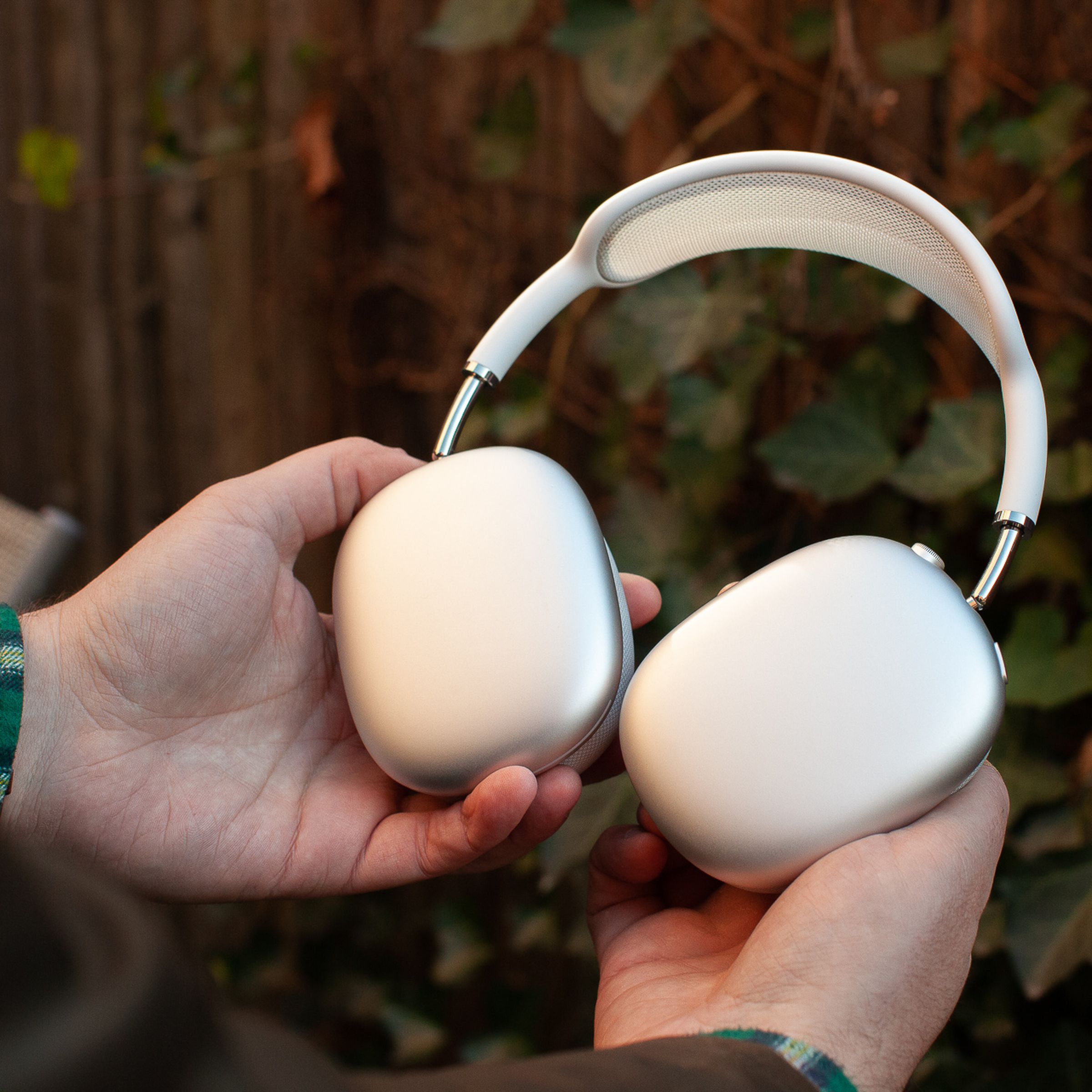 Hands holding the silver Apple AirPods Max.