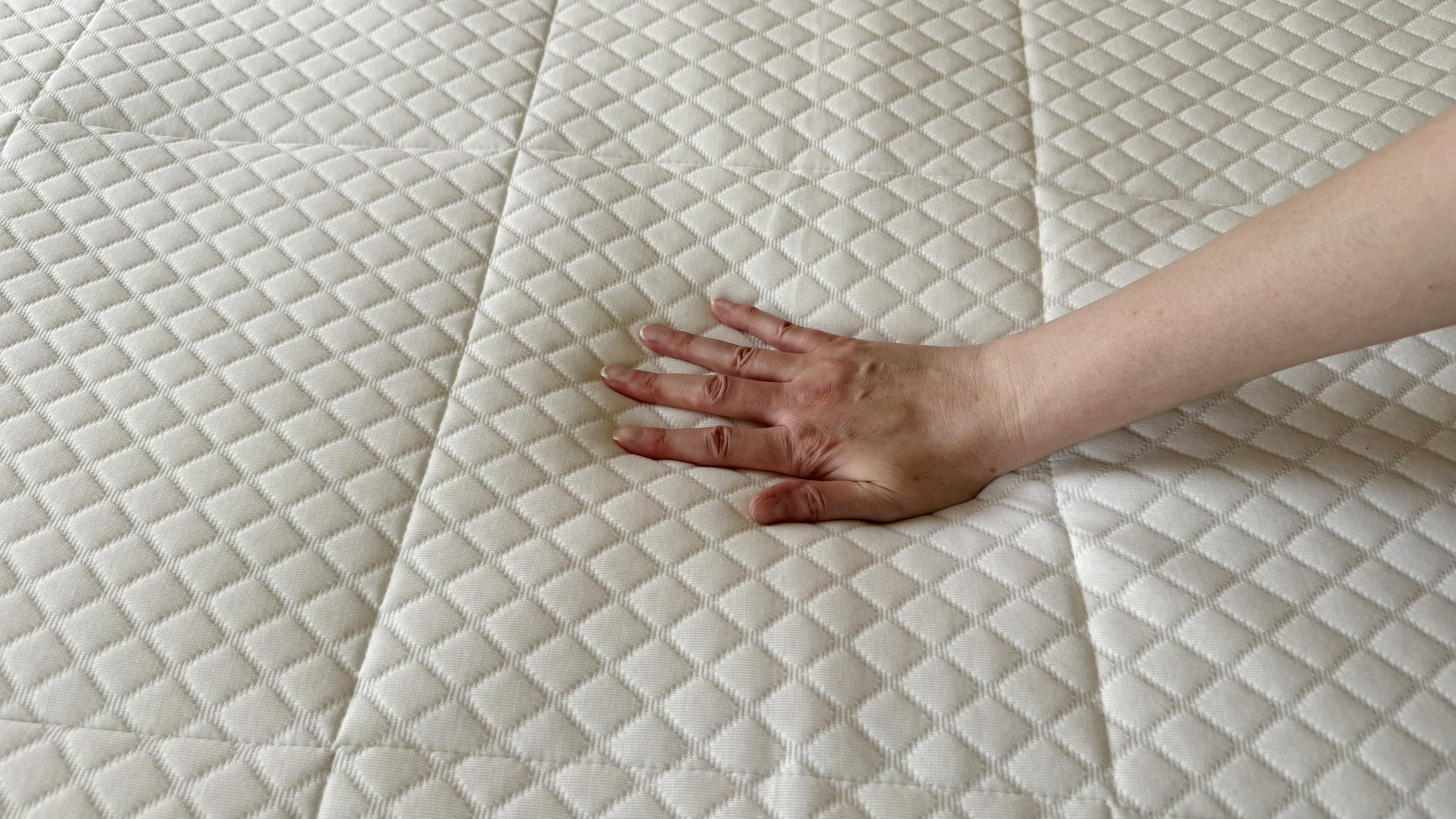 Tester's hand on the cooling cover of the Nectar Hybrid mattress