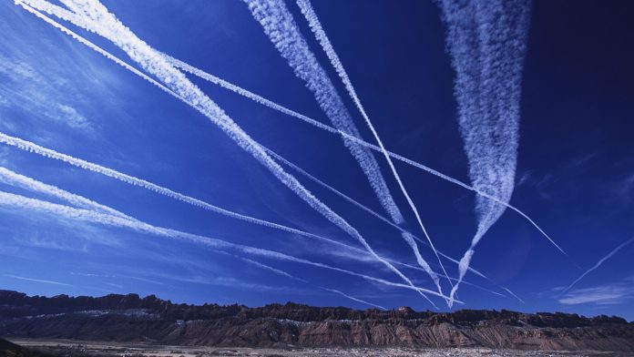 Contrail clouds from passing jet planes streak the sky over the Utah desert.