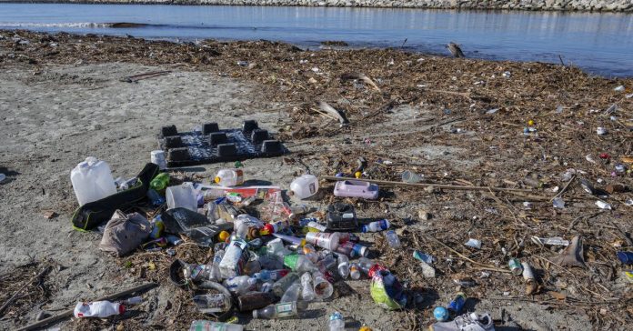 A pile of plastic bottles and other trash seen along a river bank.