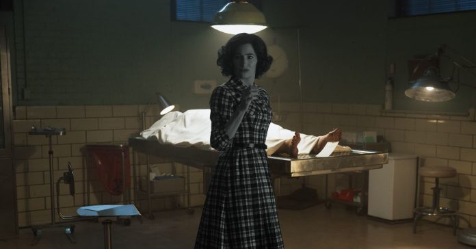 A woman drained of all color saturation standing in a fully colorized morgue.