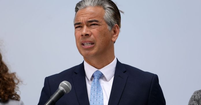 A man wearing a suit speaks into a microphone outdoors.