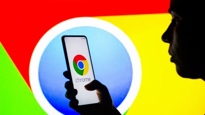  In this photo illustration, a silhouetted woman holds a smartphone with the Google Chrome logo displayed on the screen.