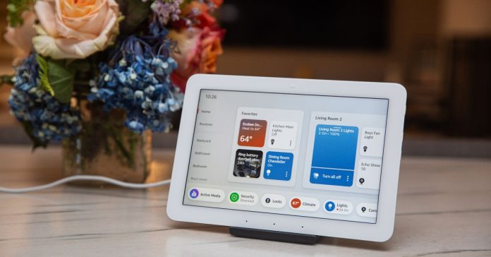 A small touchscreen tablet on a counter next to some flowers.