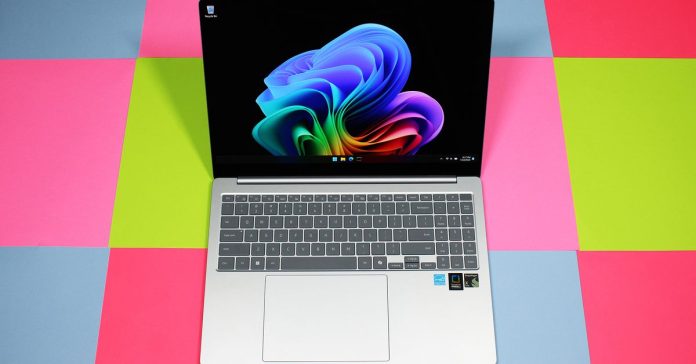 An open and powered-on silver laptop against a background of different colored squares.