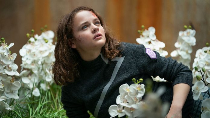 Joey King as Tally with blood on her face and lying in a bed of white orchids in Uglies.