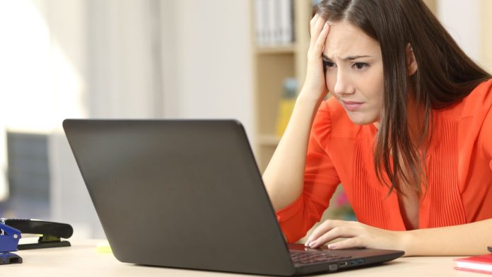 A worried woman sitting at a surface and using a laptop