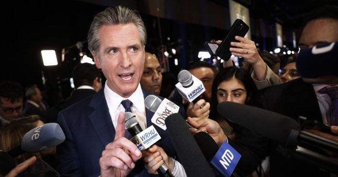 California Governor Gavin Newsom talks to journalists in the media center at the Pennsylvania Convention Center